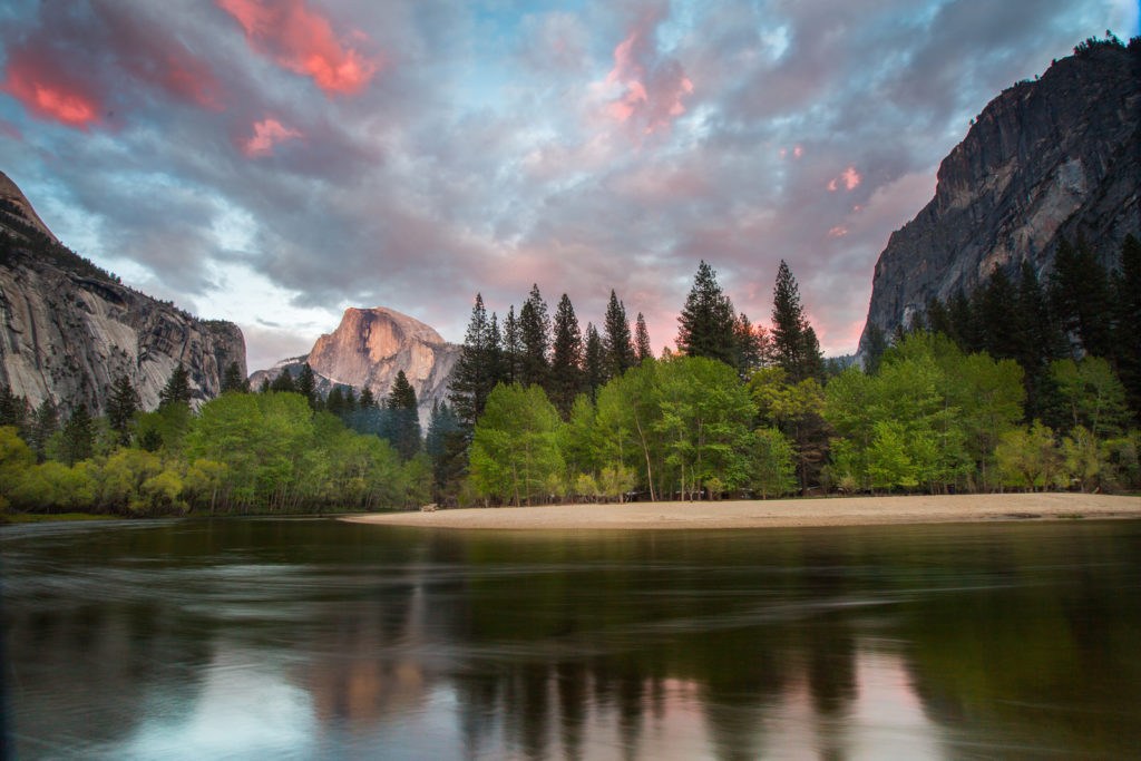 Yosemite Valley cliffs and pink clouds reflected in a river