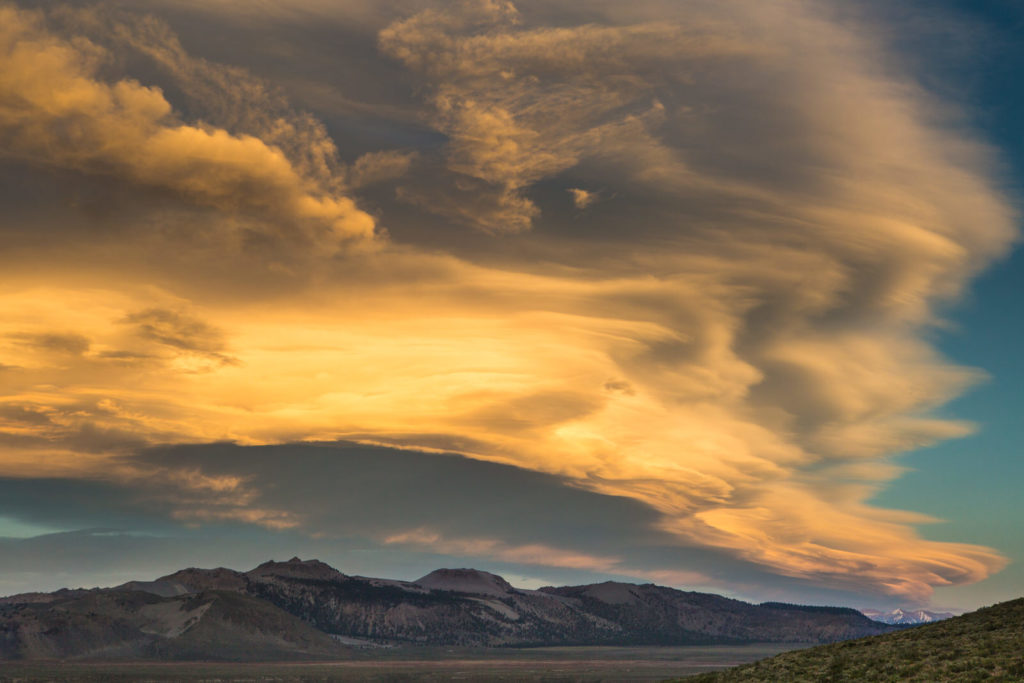 Golden clouds spreading above distant mountain ridges