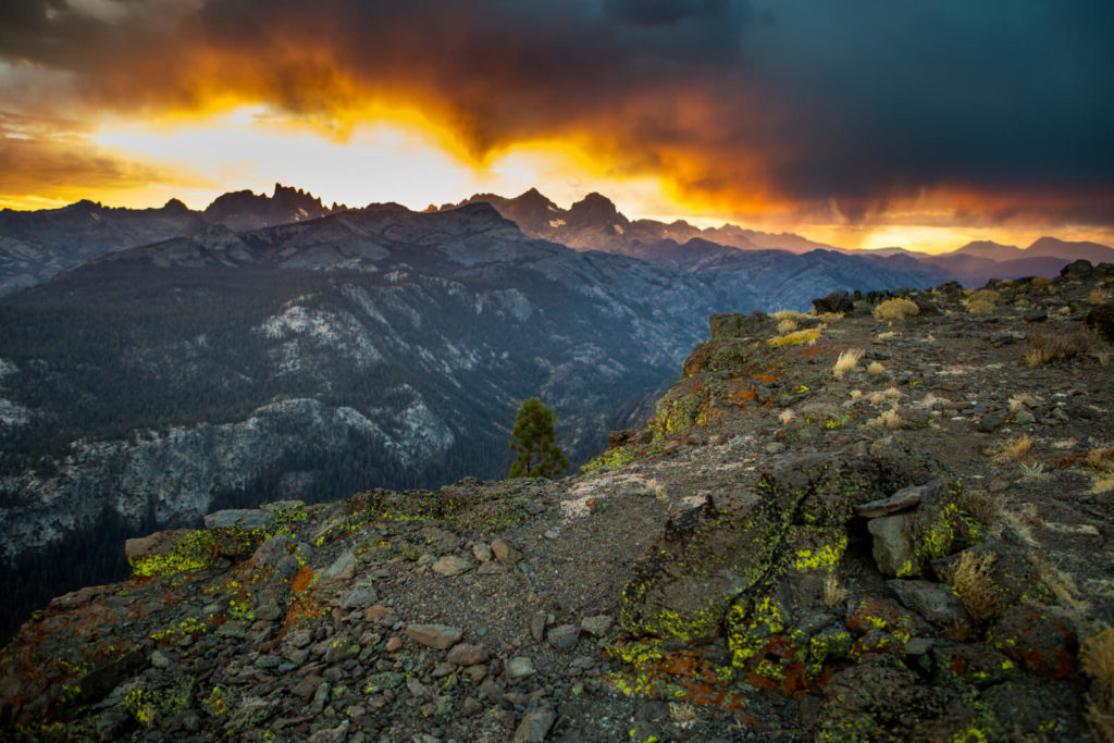 Golden storm light above layered mountain ridges and a rocky overlook