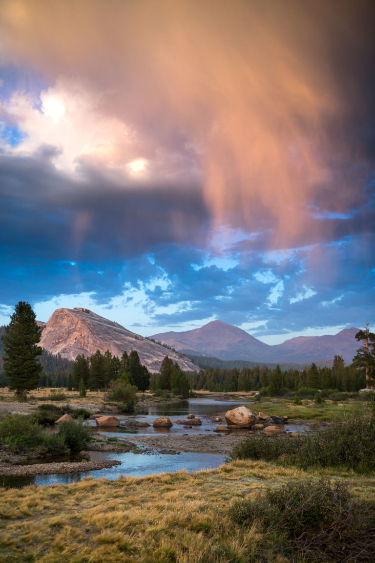 Colorful storm clouds above a granite dome and winding river