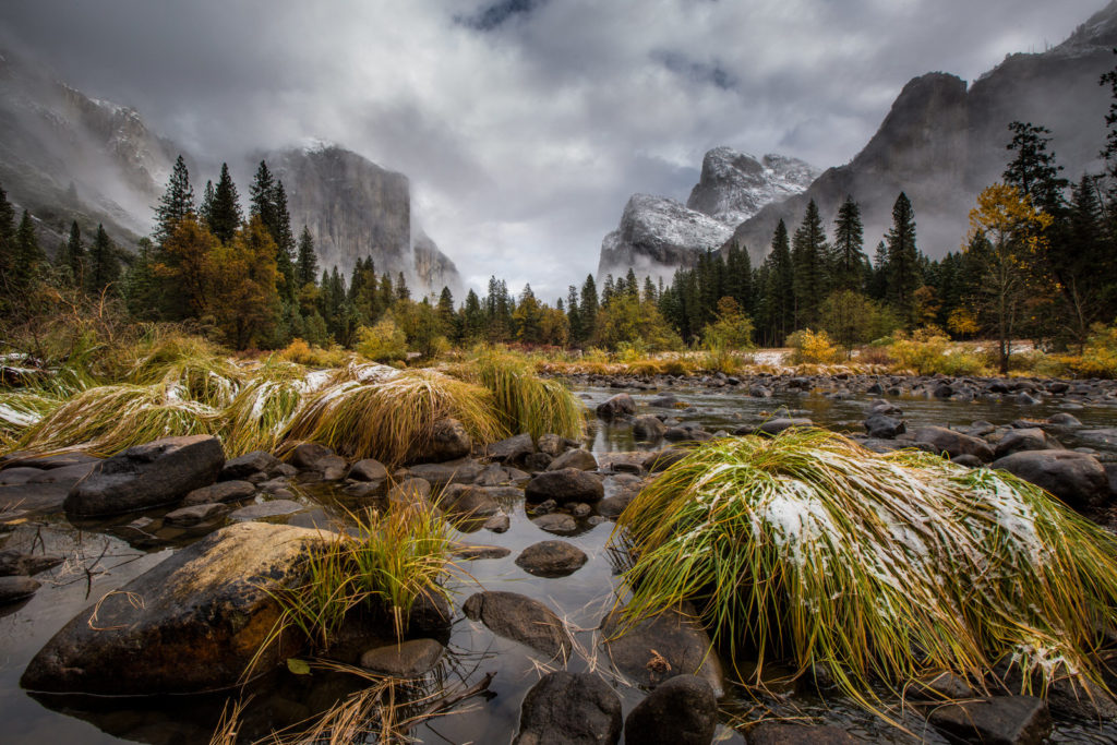 Snow-dusted Yosemite Valley cliffs above a rocky meadow stream