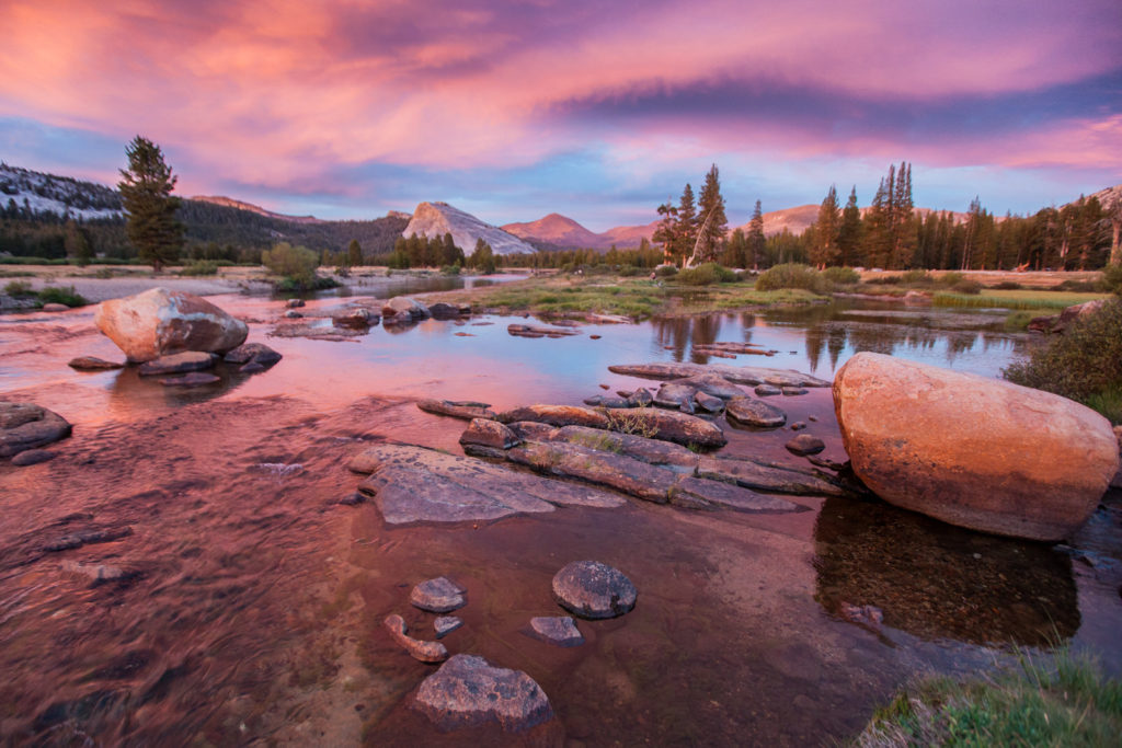 Pink sunset reflected in shallow water among granite boulders