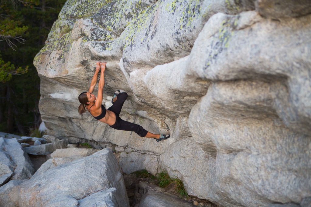 Climber hanging from a granite roof with feet braced overhead