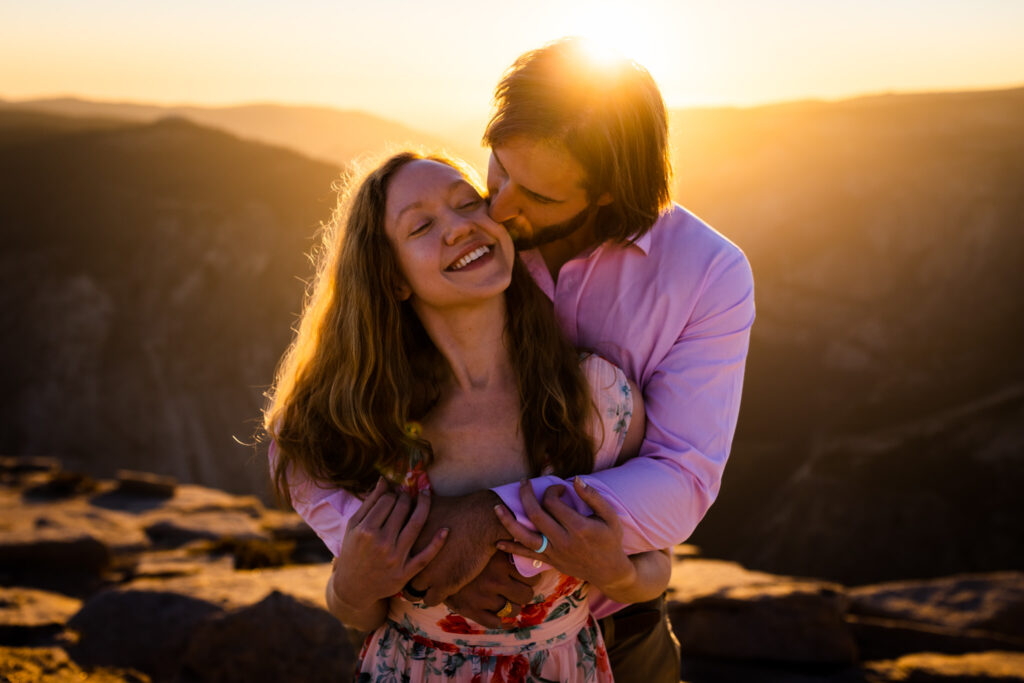 Couple laughing and embracing with the setting sun behind them