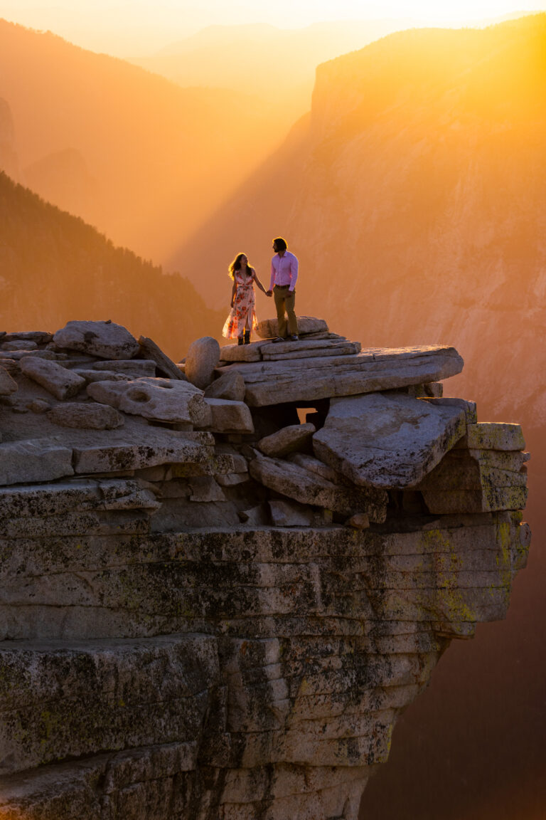 Couple standing together on a rocky ledge in golden sunset light