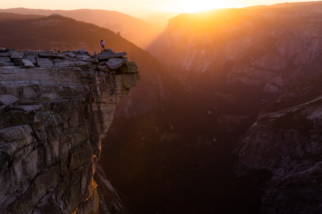 Silhouetted figures on a dramatic cliff at sunset