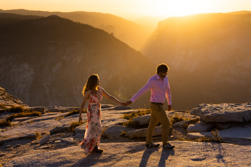 Couple holding hands on a granite overlook at sunset