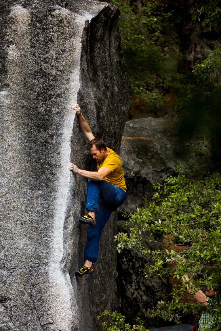Climber in a yellow top working up a narrow granite crack