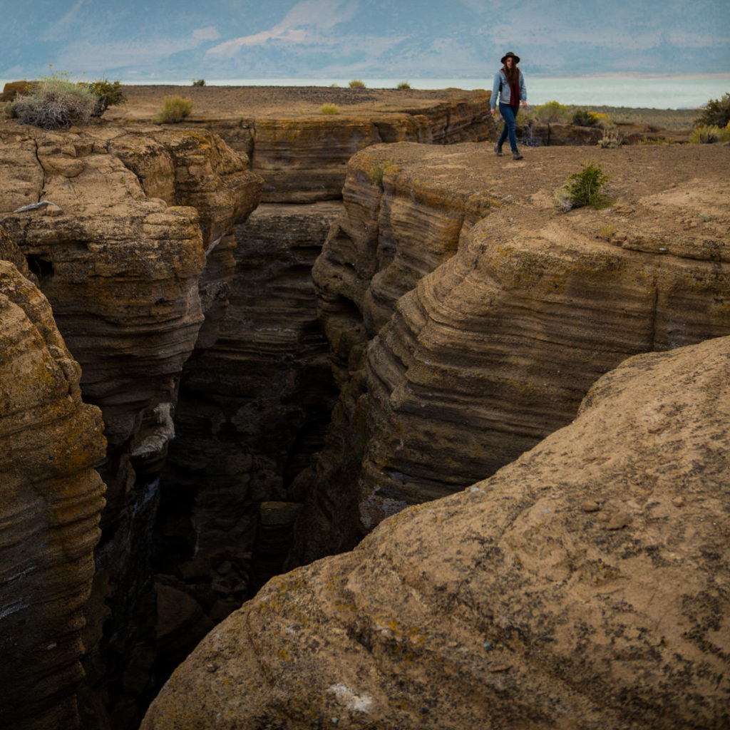 Hiker standing at the edge of a deeply eroded rocky canyon