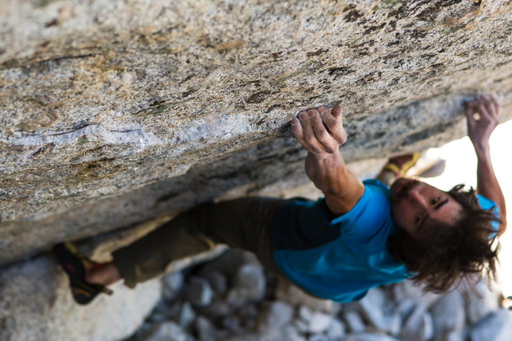 Close-up of a climber gripping the edge of an overhanging rock