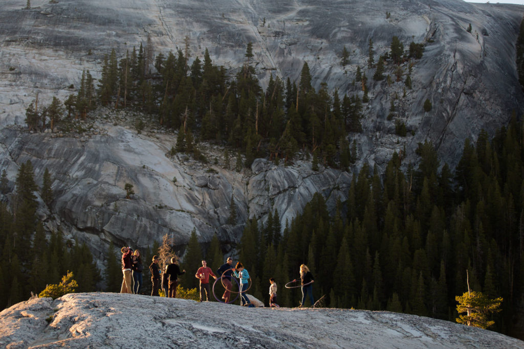 Group of hikers on a granite overlook above a forested mountain basin