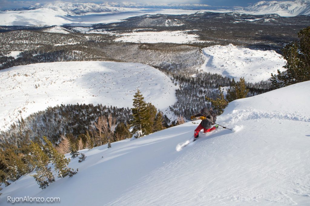 Skier carving through fresh powder on a broad mountain slope