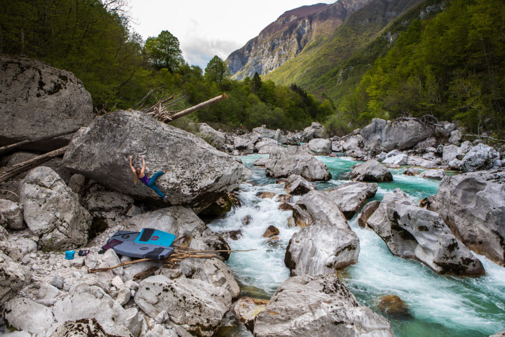 Boulderer stretched across a low rock beside a mountain river