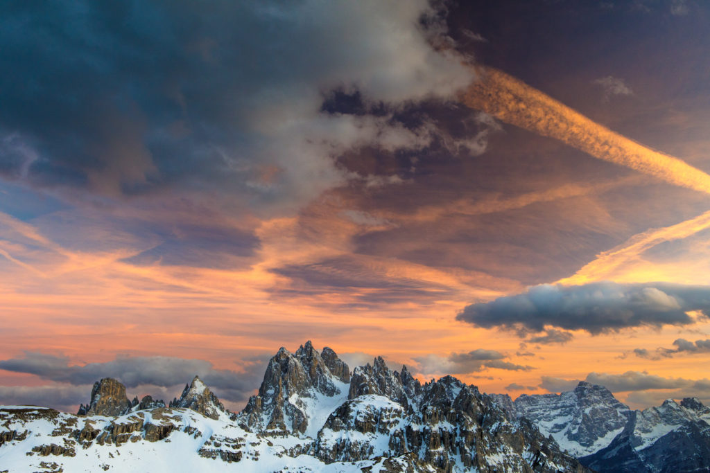 Pink and orange sunset clouds above snow-covered mountain peaks