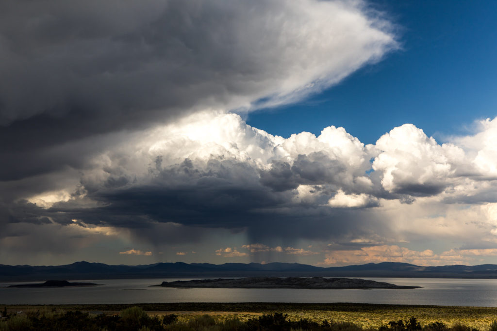 Large storm clouds above an open lake and distant mountains