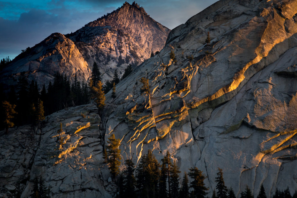 Warm evening light tracing a steep granite mountain face