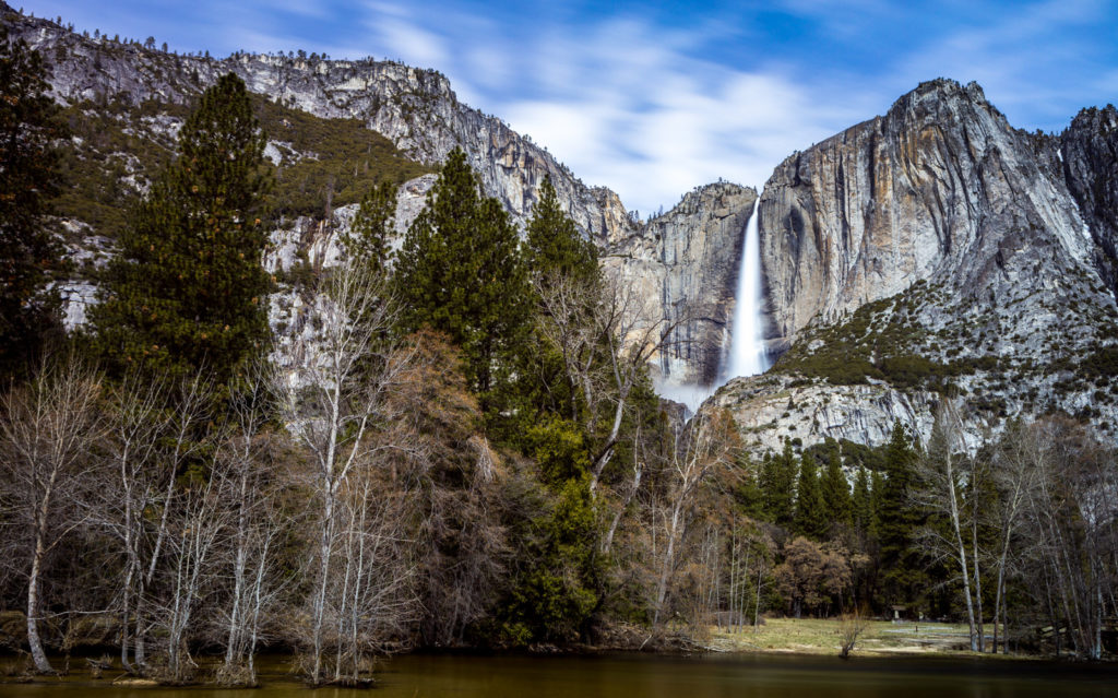 Yosemite Falls dropping between granite cliffs above spring trees