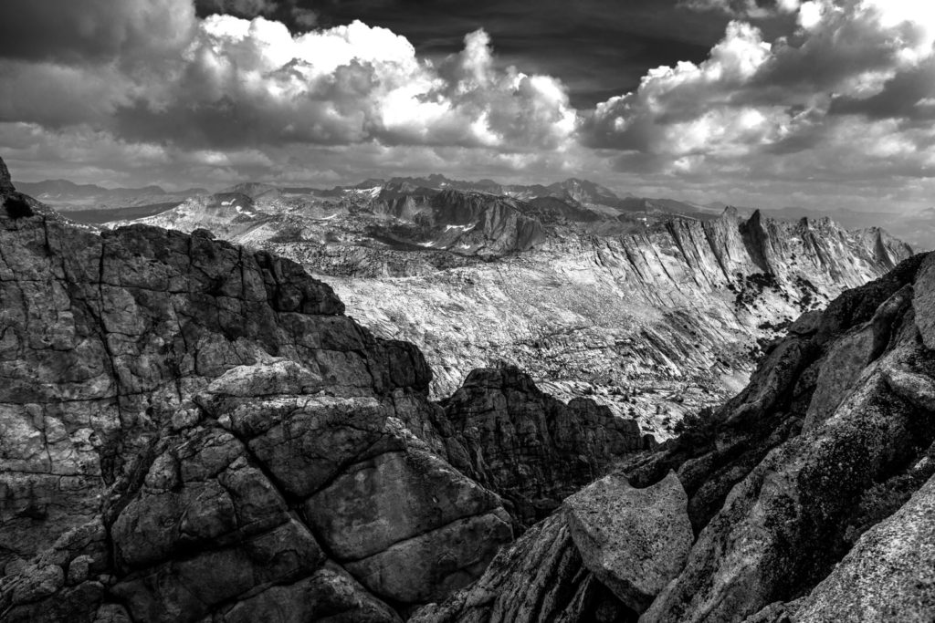 Black-and-white view across a rugged granite mountain basin