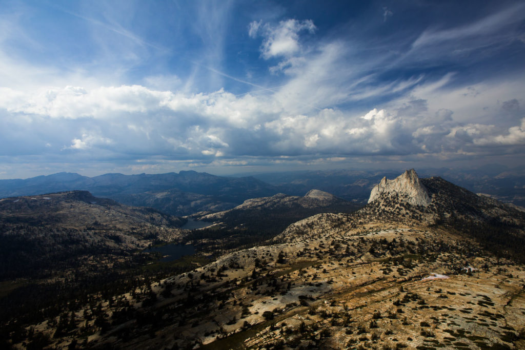 Wide view across granite ridges and forest beneath summer clouds