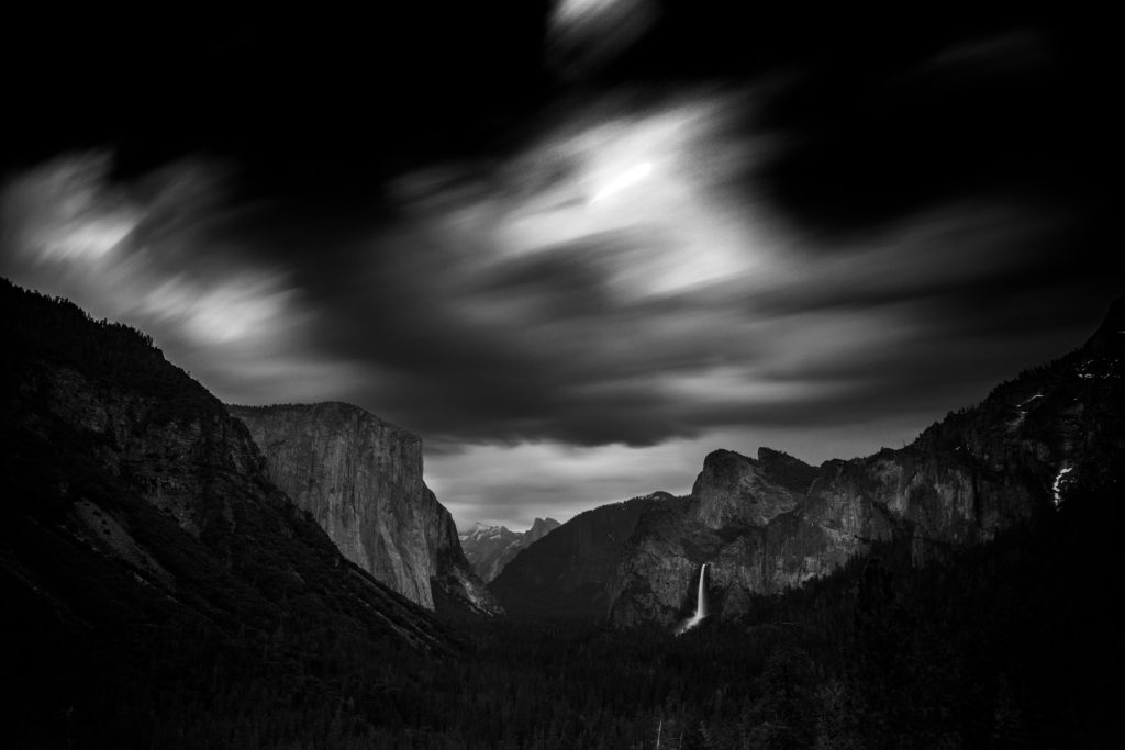 Black-and-white view of a granite valley beneath streaking clouds