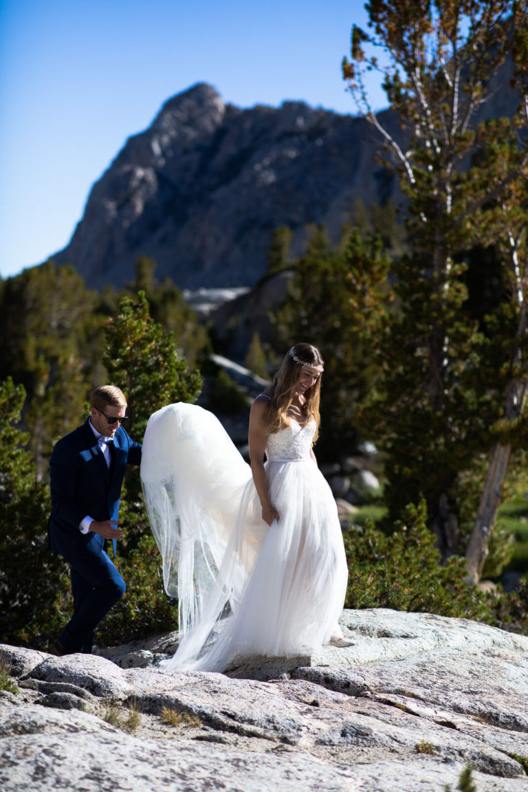 Bride lifting her dress as she walks toward the mountain ceremony