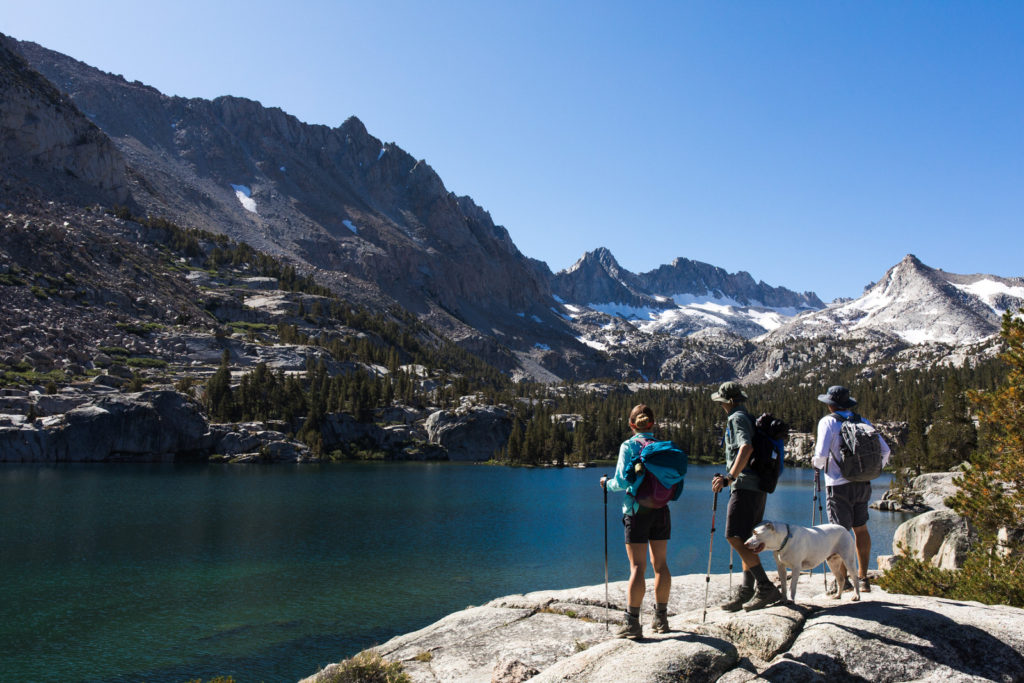 Hikers taking in the view beside a turquoise alpine lake