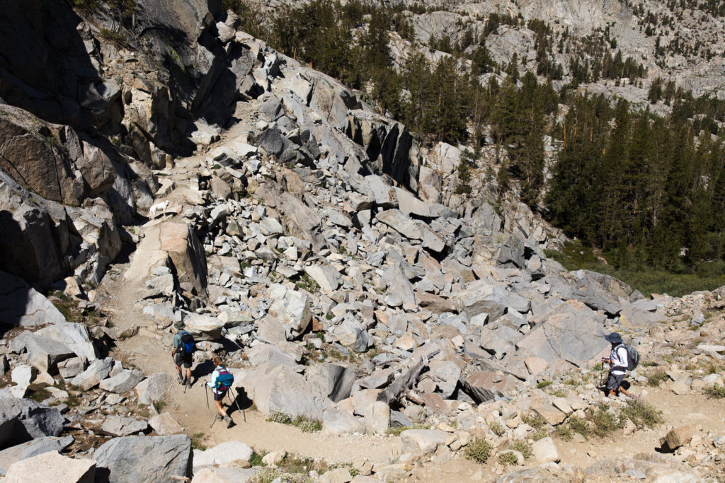 Hikers making their way across a rocky mountainside trail