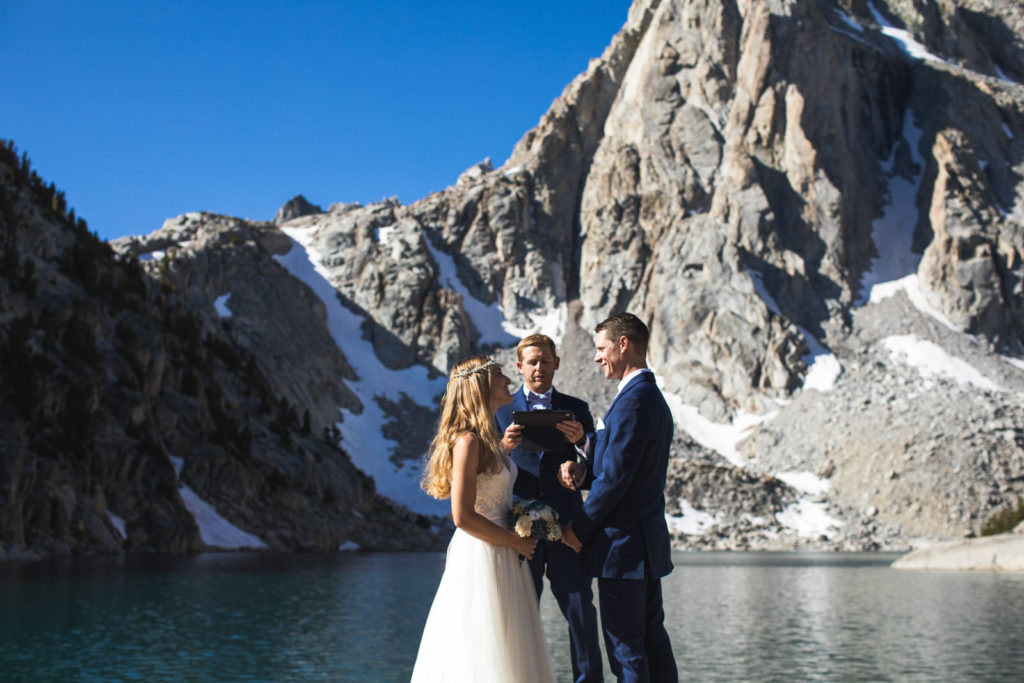 Lakeside wedding ceremony beneath snow-streaked granite peaks