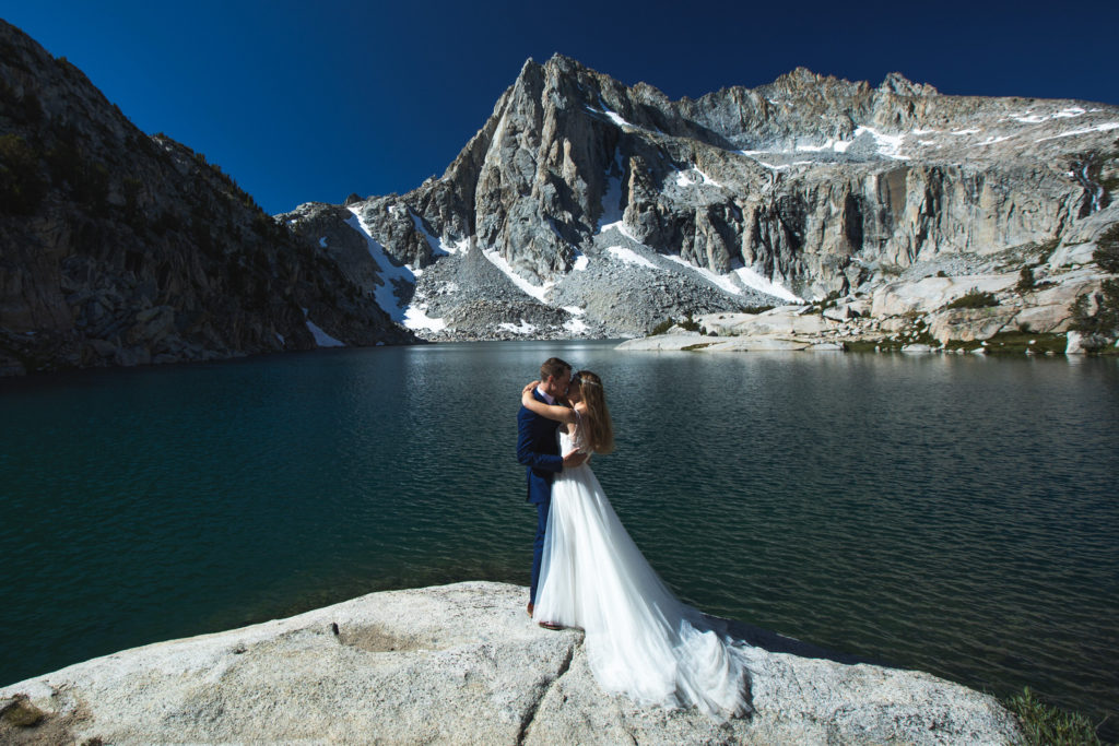 Couple embracing on a granite outcrop above a mountain lake