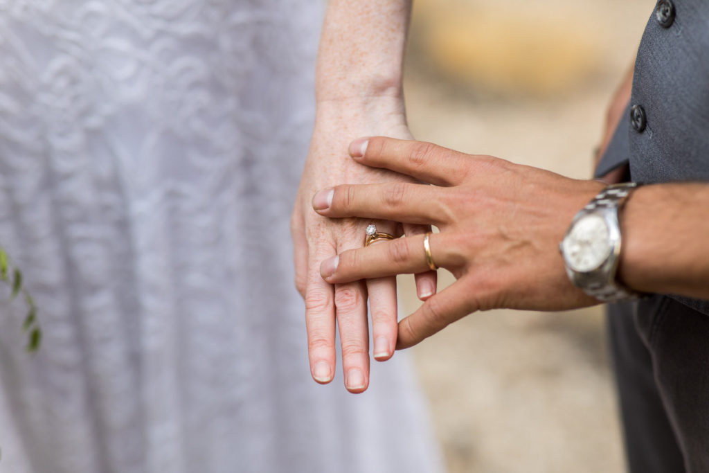 Close-up of wedding rings on the couple’s joined hands