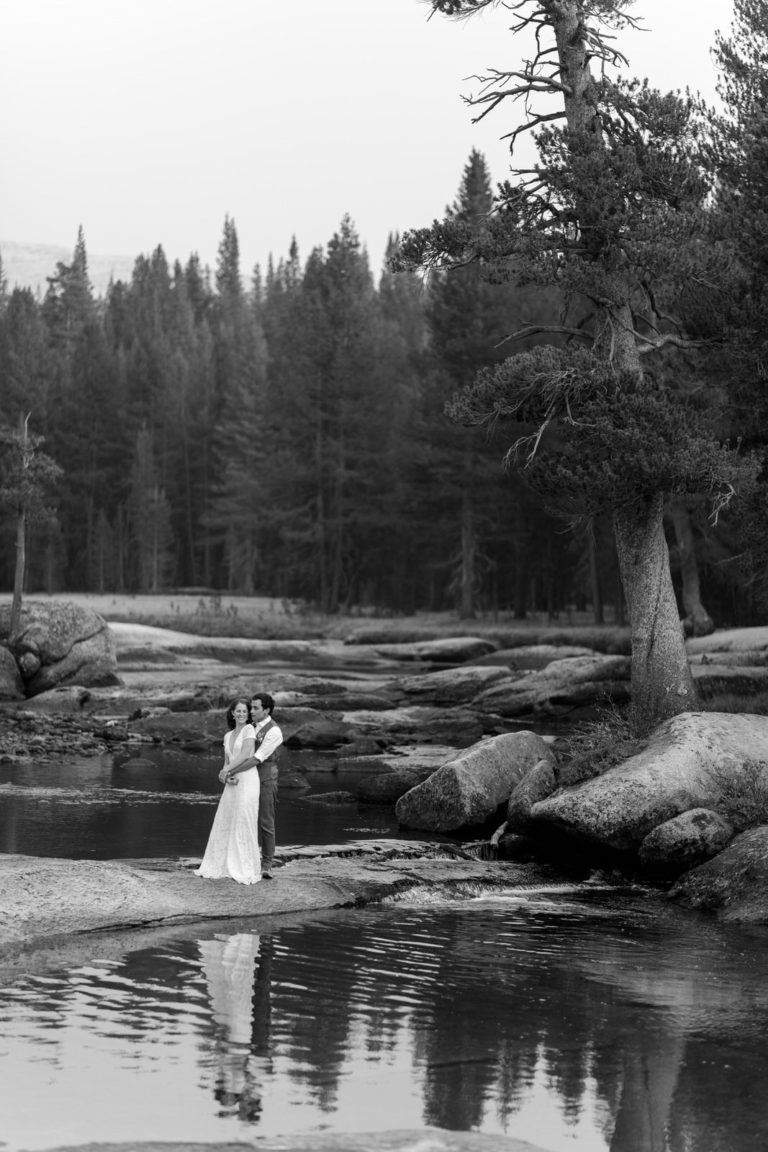 Black-and-white portrait of newlyweds reflected in a forest pond