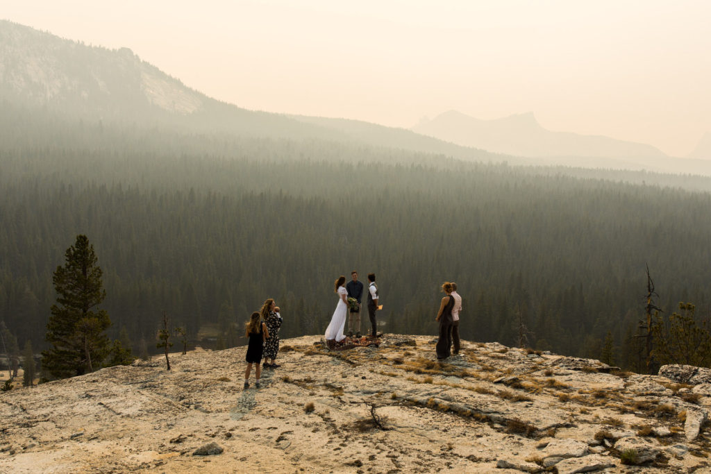 Small wedding party on a granite overlook above a forested valley