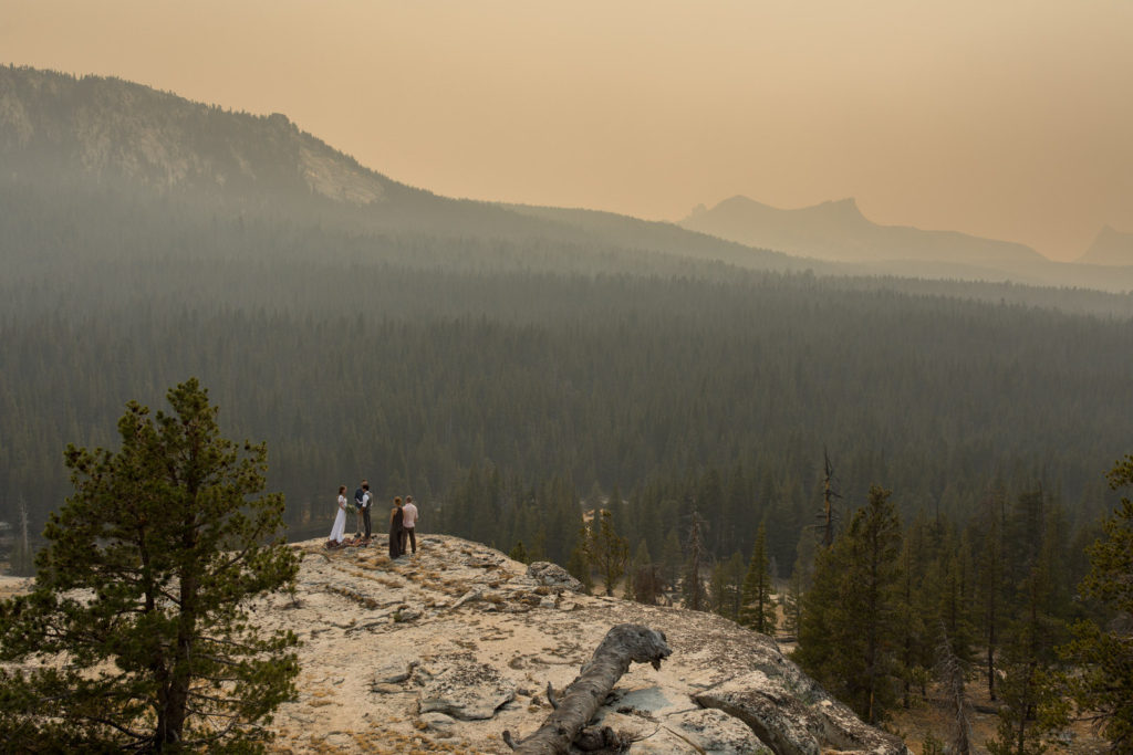 Distant view of an intimate wedding ceremony above a forested valley