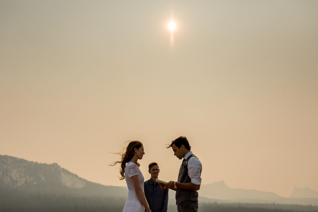 Couple exchanging vows beneath a hazy sun on a mountain overlook