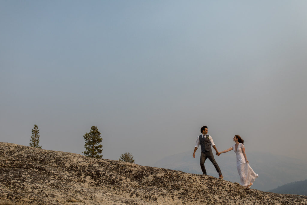 Couple walking hand in hand across a granite ridge