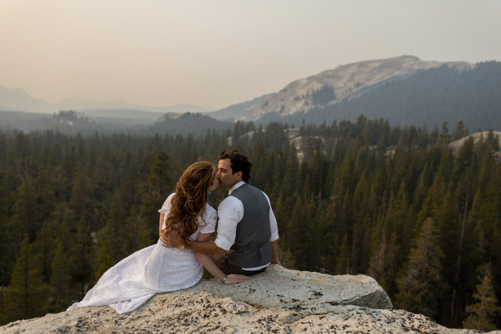 Couple embracing above the forest with distant mountains behind them