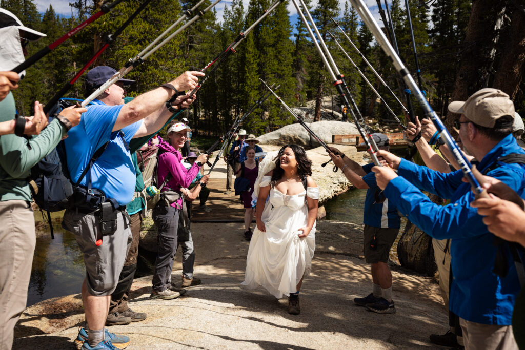 Wedding guests raising hiking poles in an arch for the newlyweds