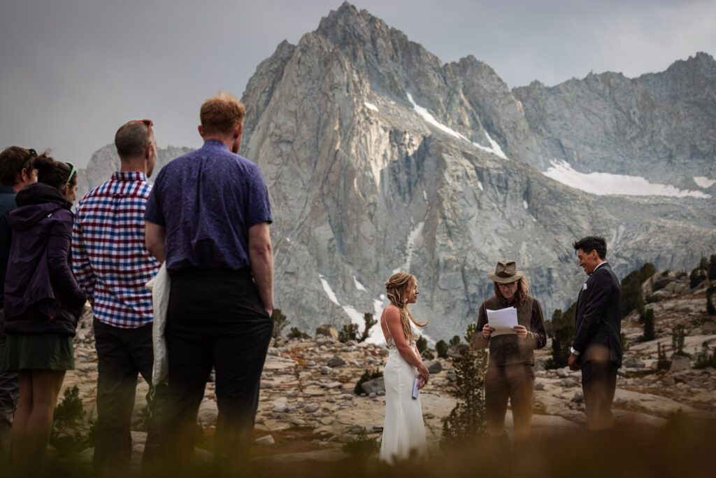 Guests watching a mountain wedding ceremony beneath granite peaks
