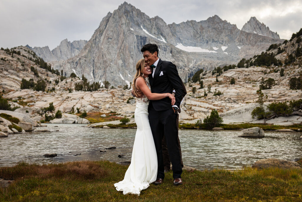 Couple embracing beside a mountain lake after their ceremony