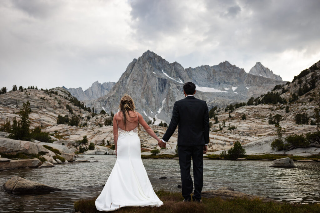 Newlyweds holding hands and looking toward the mountain skyline