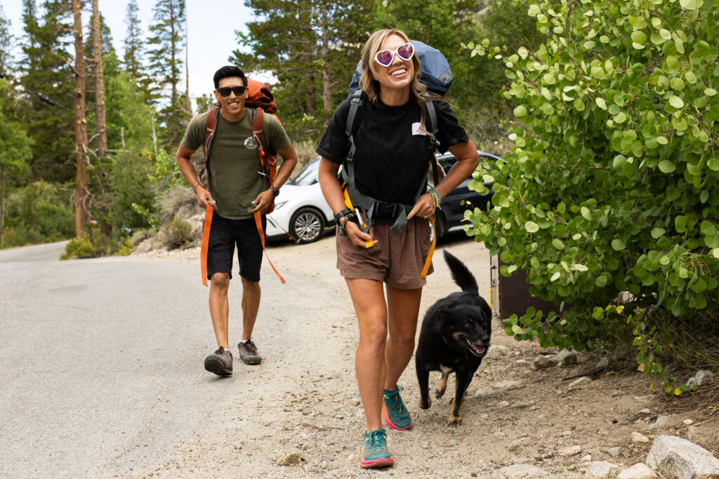 Couple setting off with backpacks and their dog at a forest trailhead