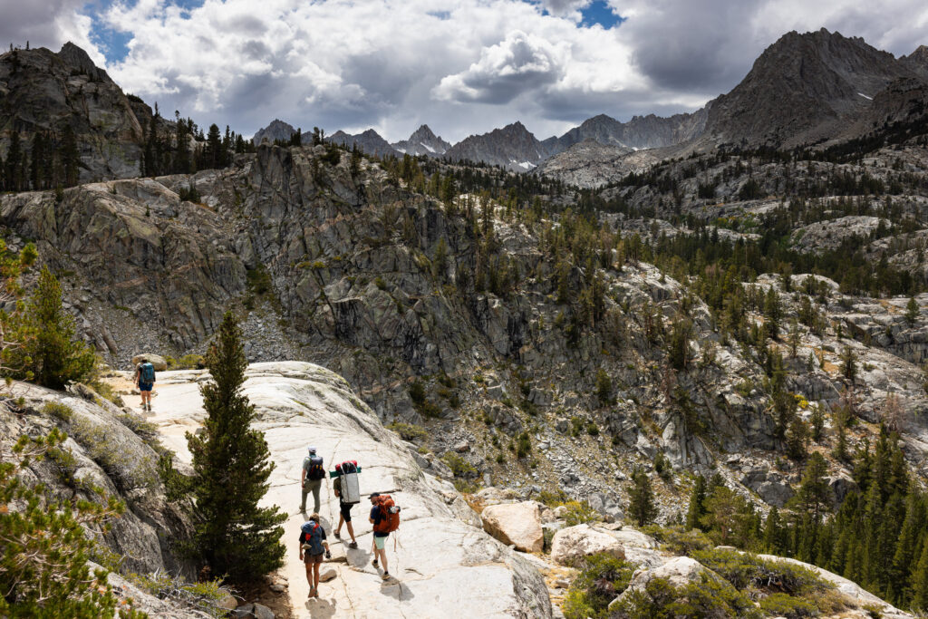 Wedding group hiking across granite through a high mountain basin