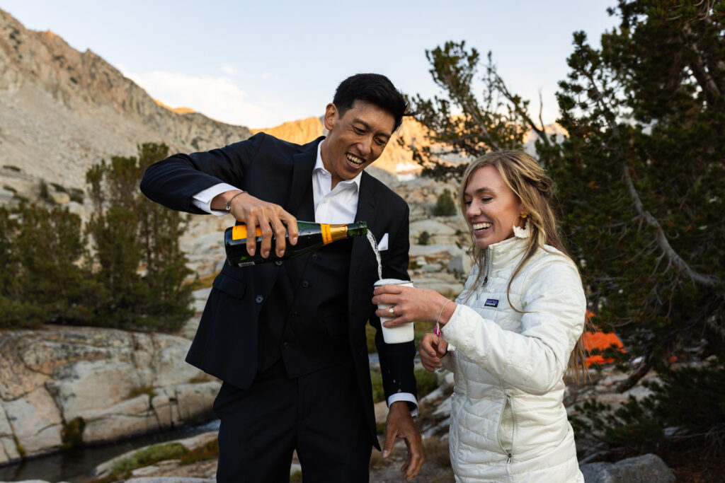 Groom pouring a celebratory drink for the bride at their campsite