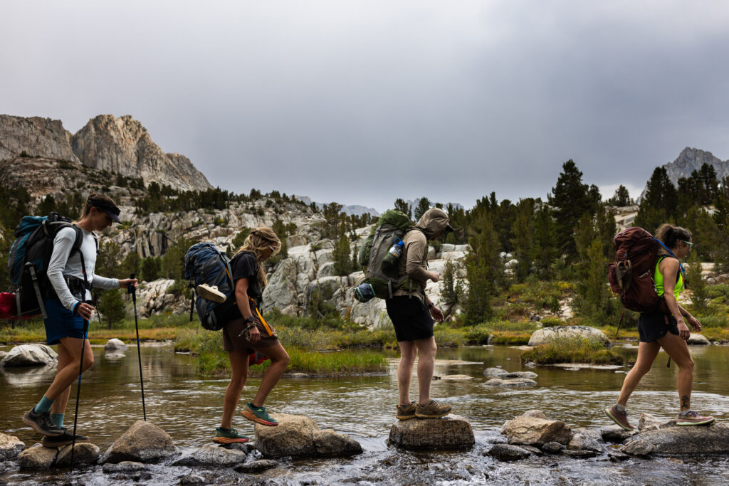 Backpackers crossing a stream on stepping stones