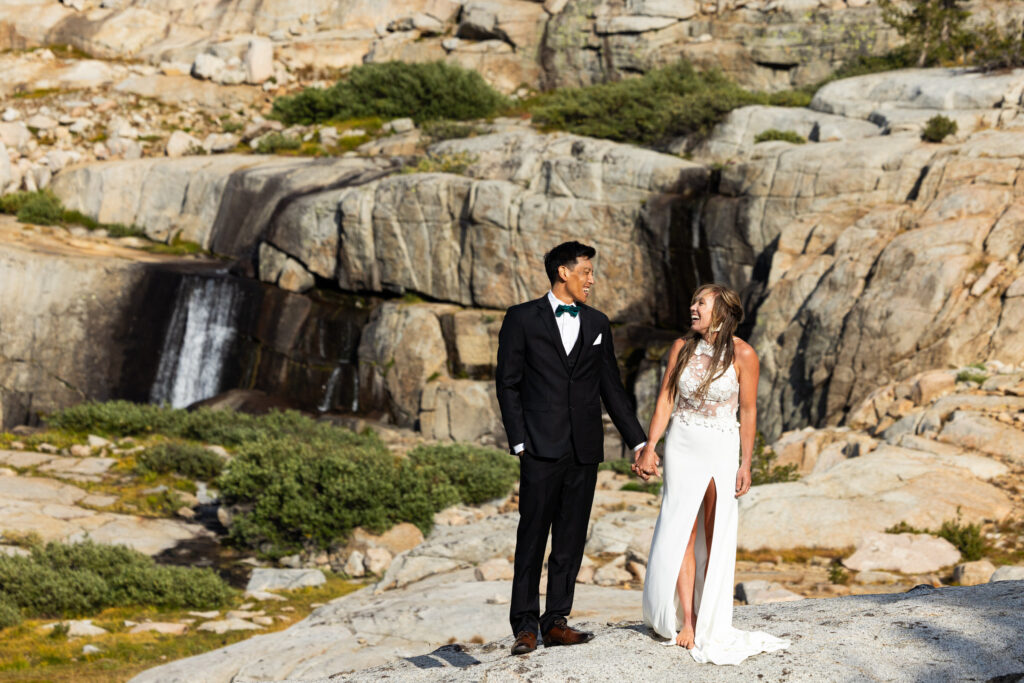Newlyweds walking hand in hand past a mountain waterfall