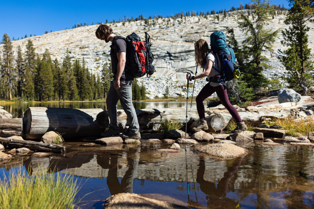 Backpackers crossing a stream on a fallen log