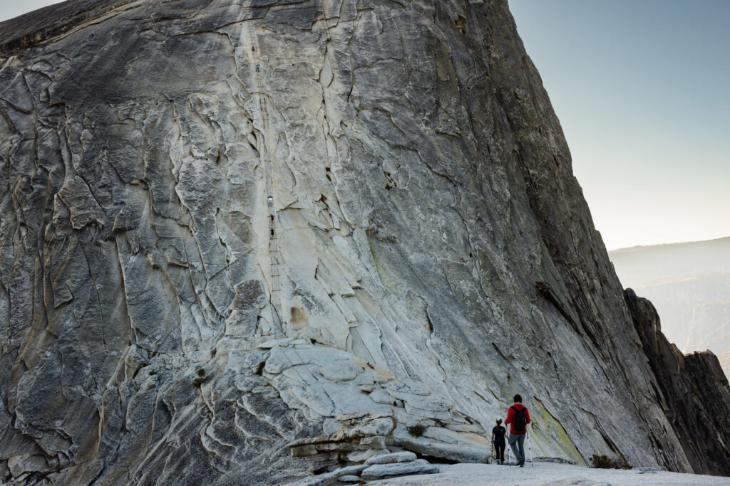 Hikers beneath a towering granite wall