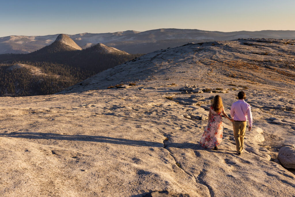 Couple walking away together across a broad granite ridge