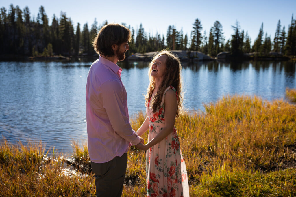 Couple holding hands beside a sunlit forest lake