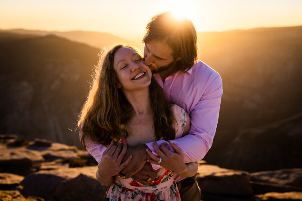 Man kissing his partner’s cheek as she laughs in the sunset light